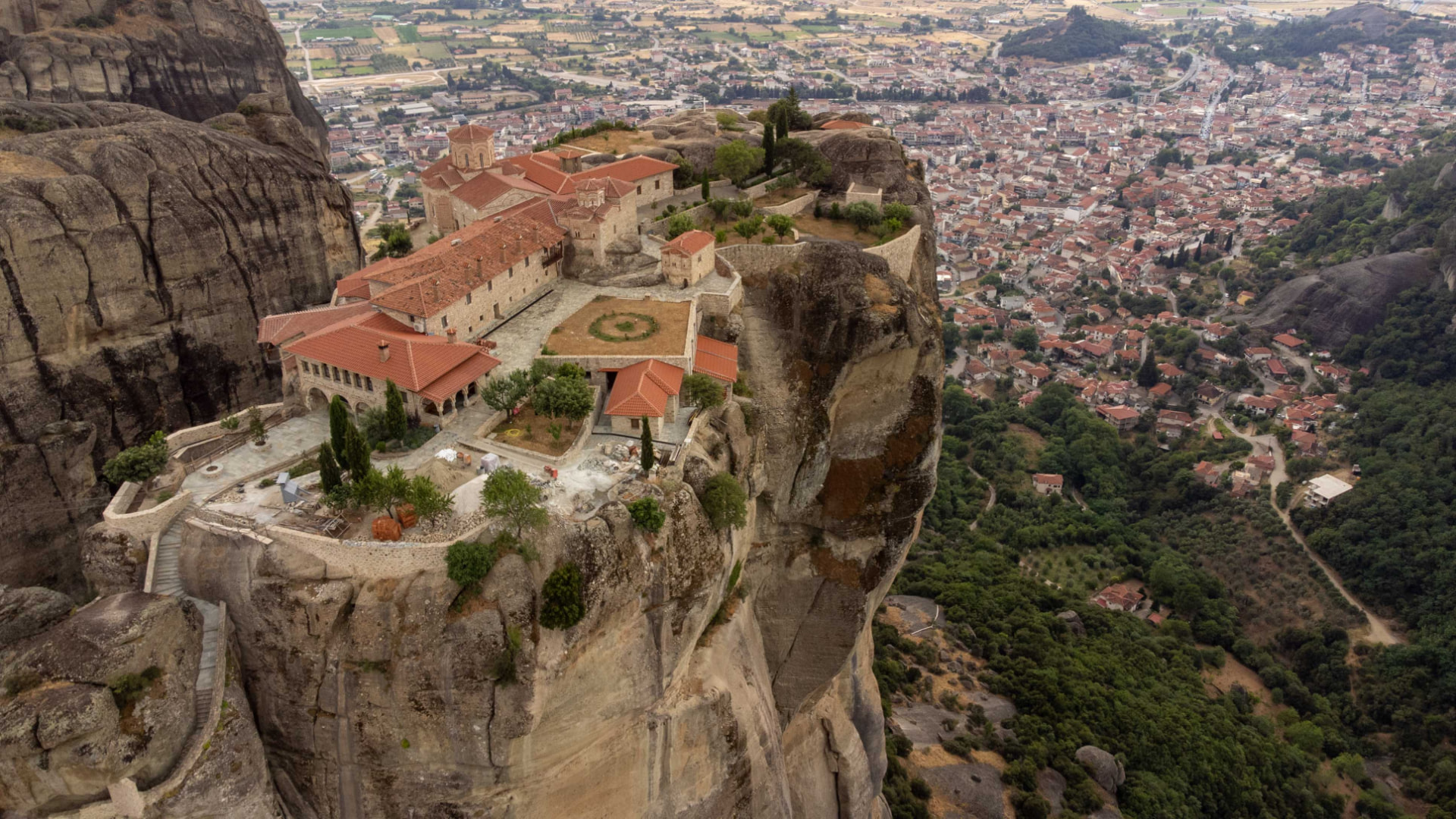 Ancient monastery perched on a dramatic rock pillar above a valley town
