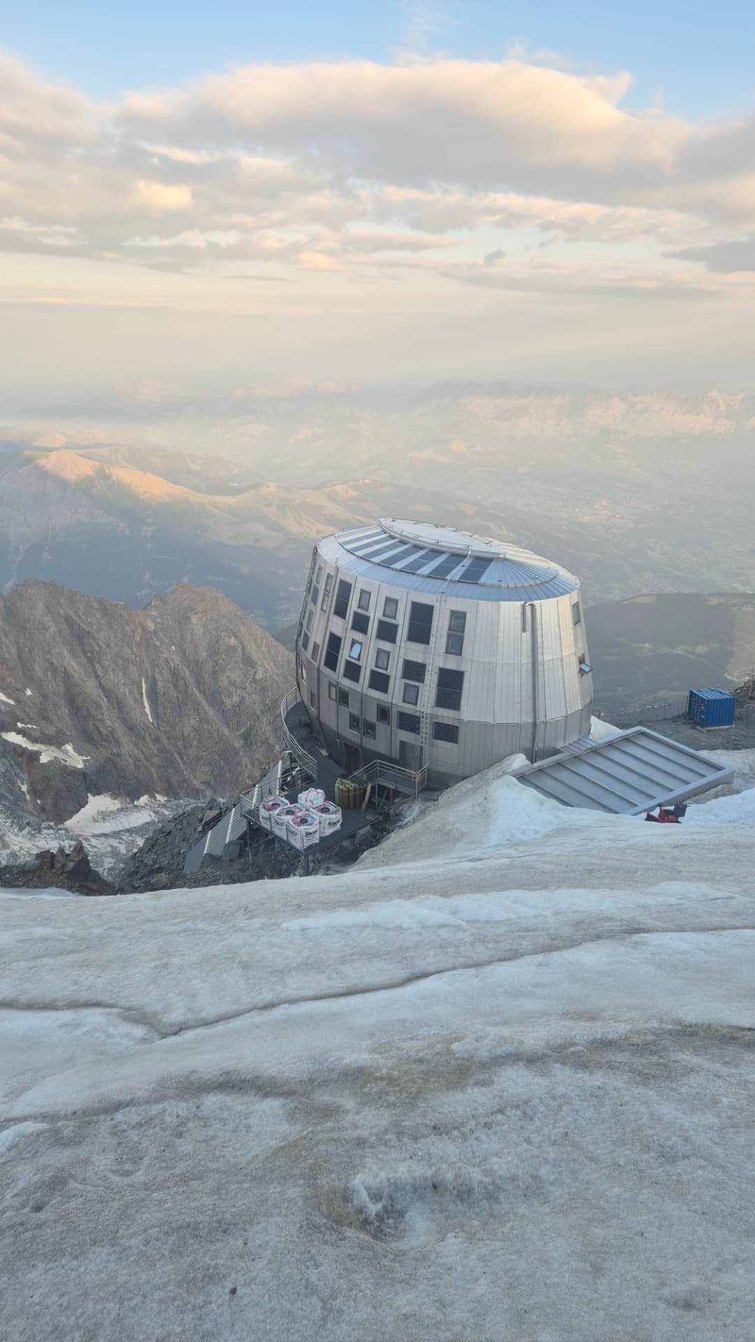 Modern circular mountain refuge perched on a snowy Mont Blanc ridge at sunset