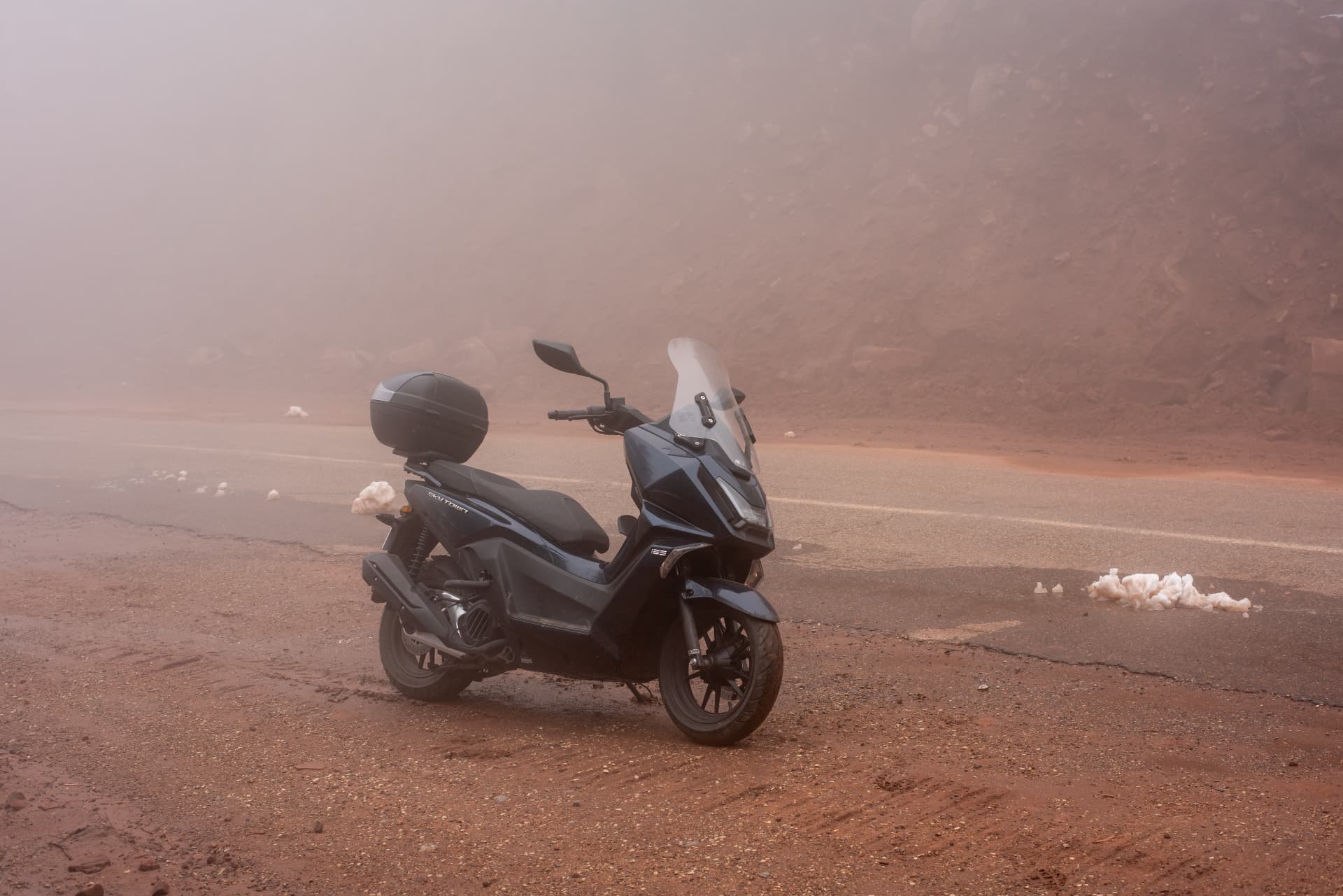 Black scooter parked on a foggy mountain road in Morocco